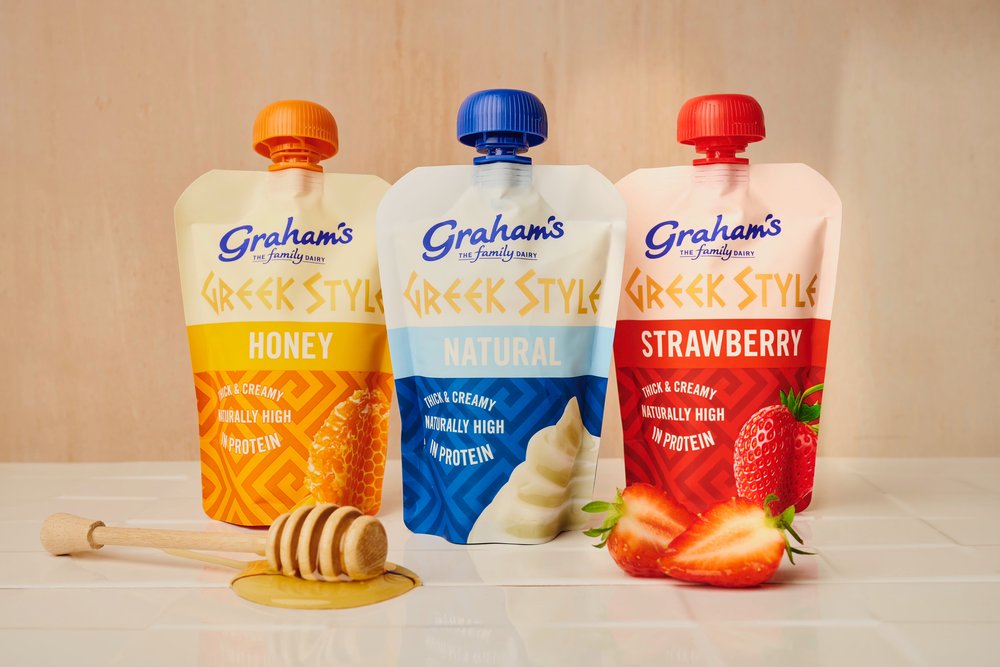 Graham's Greek yogurt pouches beside strawberry and honey