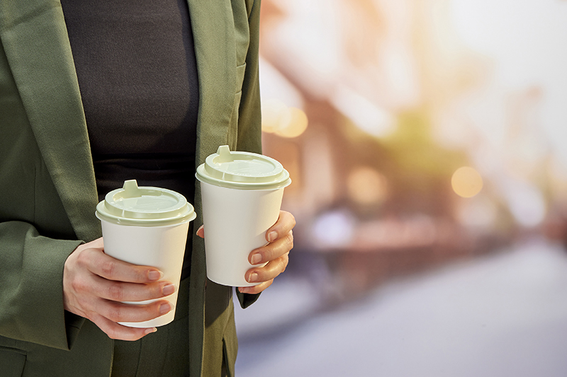 Man holding two coffee cups with sustainable lids