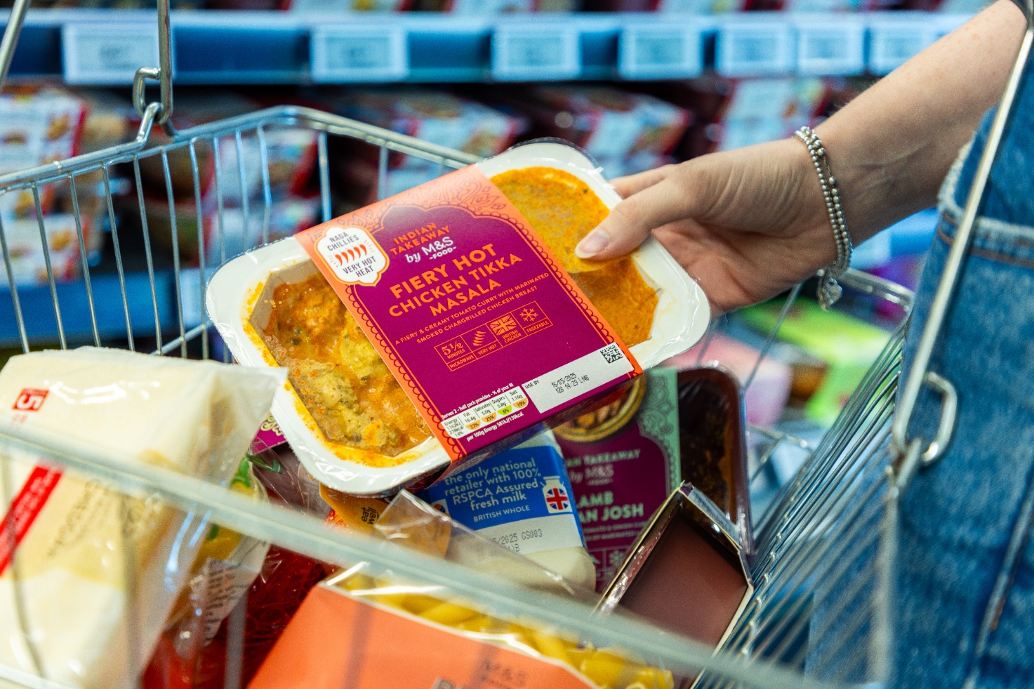 Person holding M&S ready meal over basket
