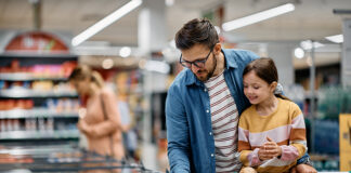 Shoppers looking at food packaging labels in supermarket