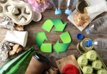 Recycling symbol and different garbage on wooden background, top view