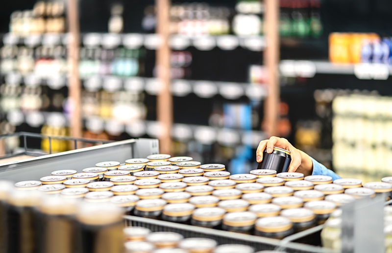 Retail worker filling shelf with cans in grocery store