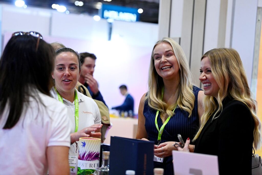 Women at trade show surrounded by cosmetics packaging
