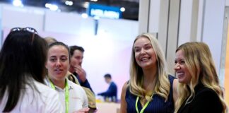 Women at trade show surrounded by cosmetics packaging