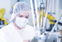 Woman in factory using tablet with robot handling cookies