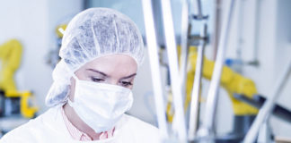 Woman in factory using tablet with robot handling cookies